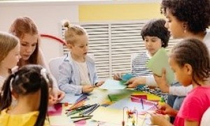 Early elementary students at a table working with manipulatives with two teachers